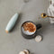 editorial image of  mint electric milk frother with gold accents and coffee drink