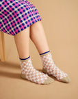 model wearing sheet and white checkered socks with feather like accents and tan/navy trim