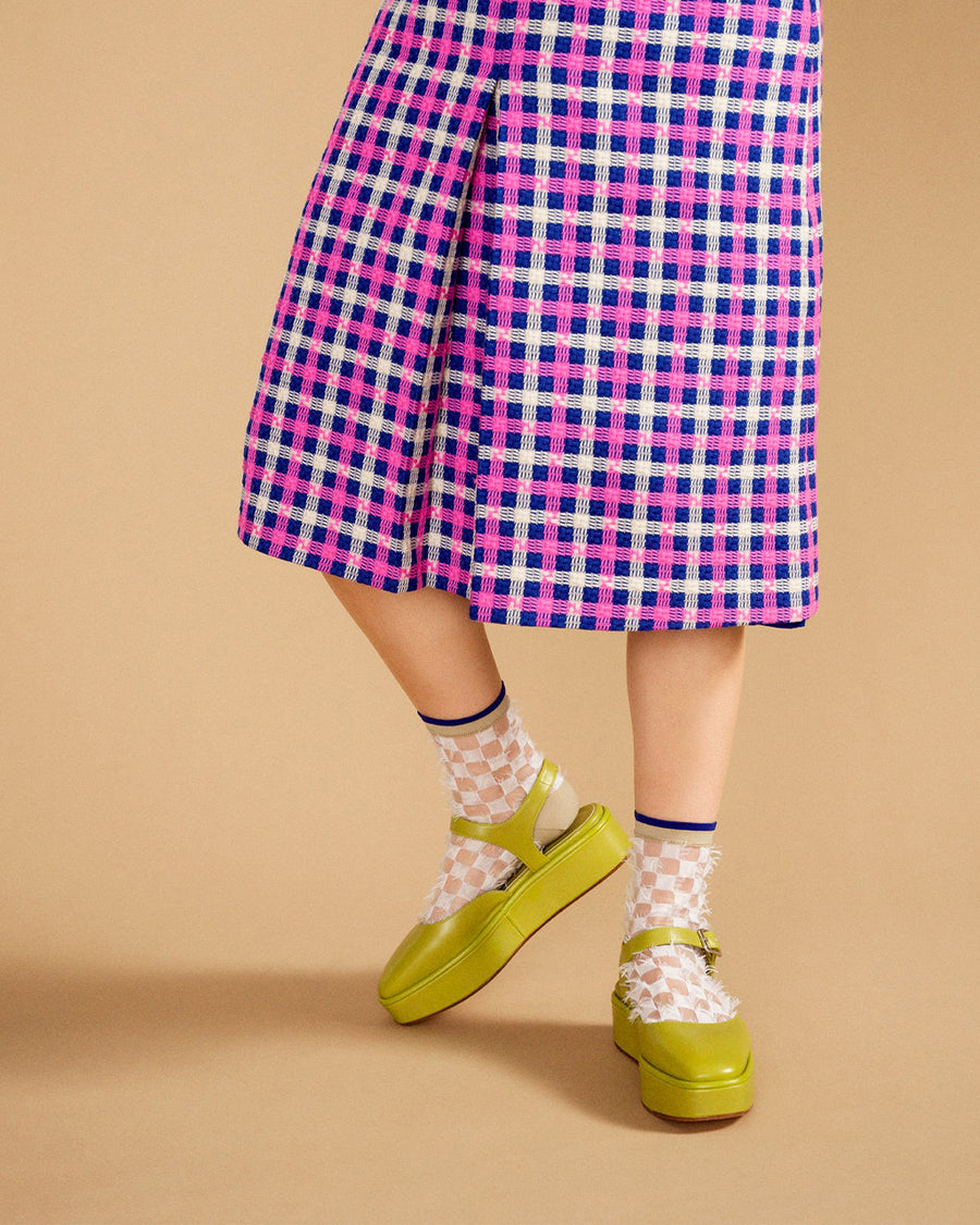 model wearing sheet and white checkered socks with feather like accents and tan/navy trim with lime green sandals