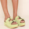 model wearing platform suede slide sandals with thick straps and metal buckle closures in pistachio green. shown from shin down