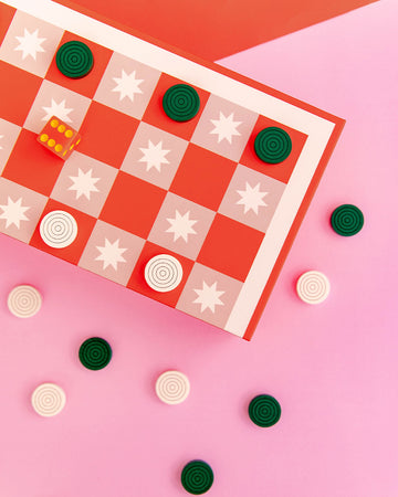 up close editorial image of pink adn red checker board with green and white pieces