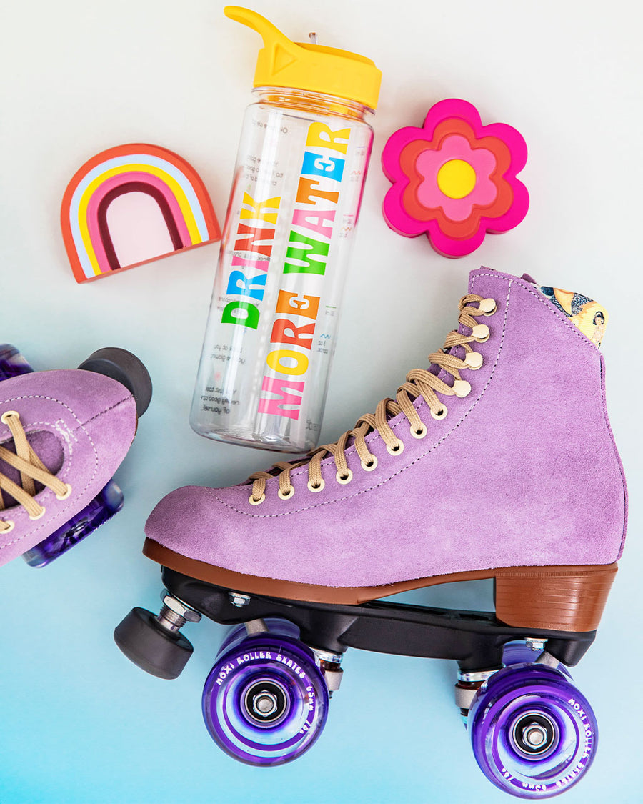 editorial image of lilac moxi roller skates, drink more water water bottle and rainbow and flower de-stress ball