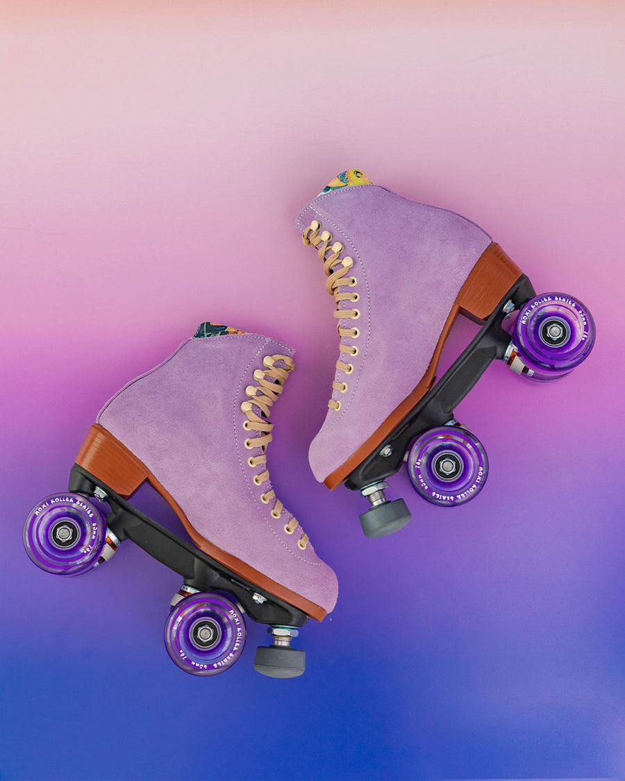 pair of lilac moxi roller skates on pink and purple ombre background