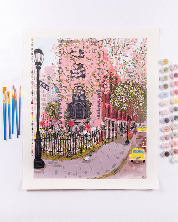 painted image of the east village with pink spring flowers surrounding it and with paints and brushes on the side