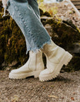 sideview of model wearing white combat style booties with thick sole and inside zipper