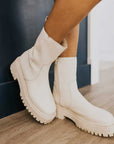 sideview of model wearing white combat style booties with thick sole and inside zipper