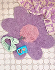 lavender daisy shaped rug with self-care items on it