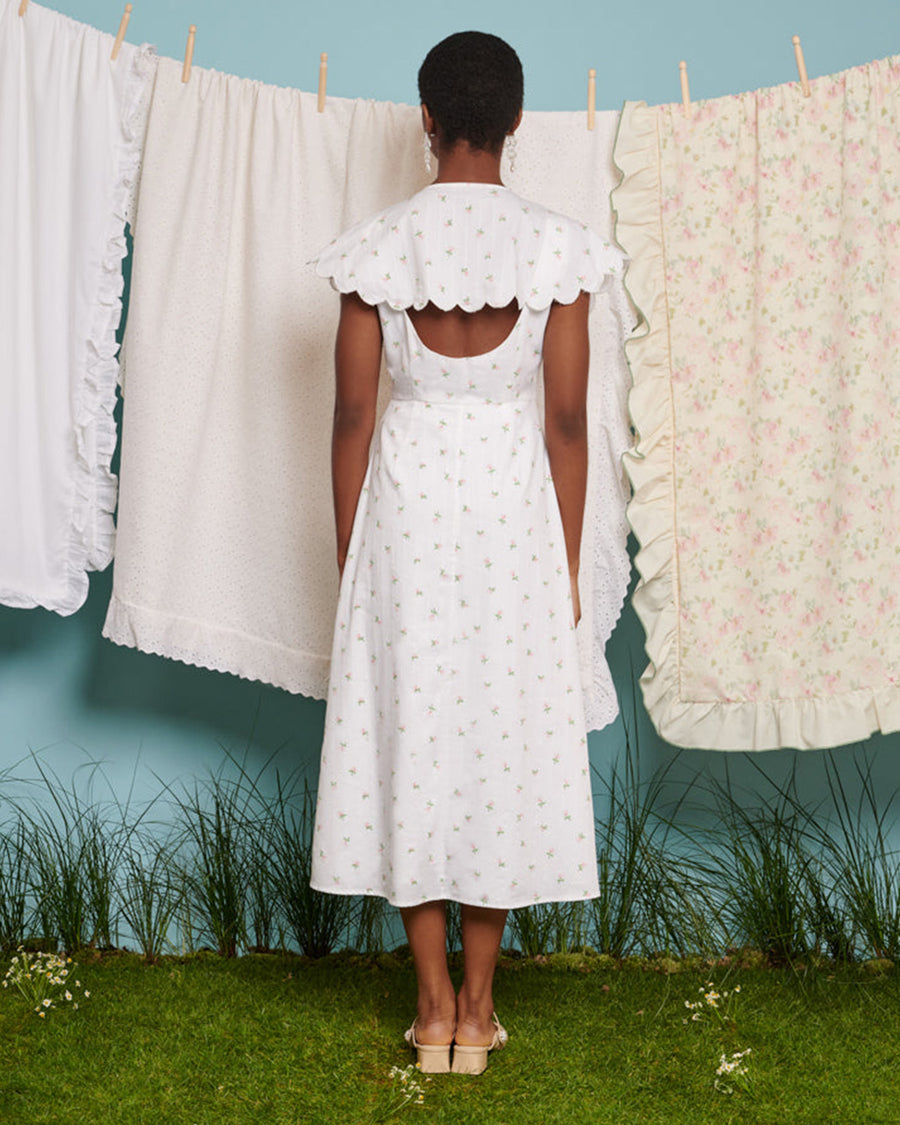backview of model wearing midi white dress with oversized collar, pink gem buttons and all over dainty floral print