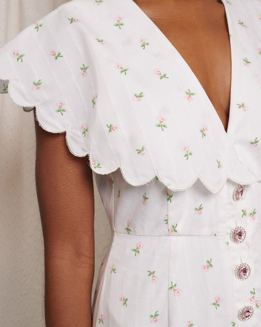 up close of model wearing midi white dress with oversized collar, pink gem buttons and all over dainty floral print