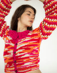 model wearing pink, orange and white crochet cropped cardigan with crochet collar