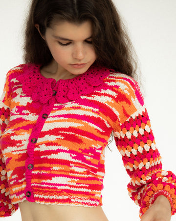 model wearing pink, orange and white crochet cropped cardigan with crochet collar