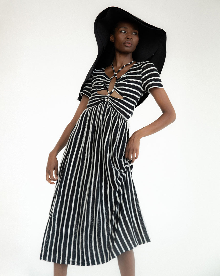 model wearing black and white stripe midi dress with cut out front and black floppy hat