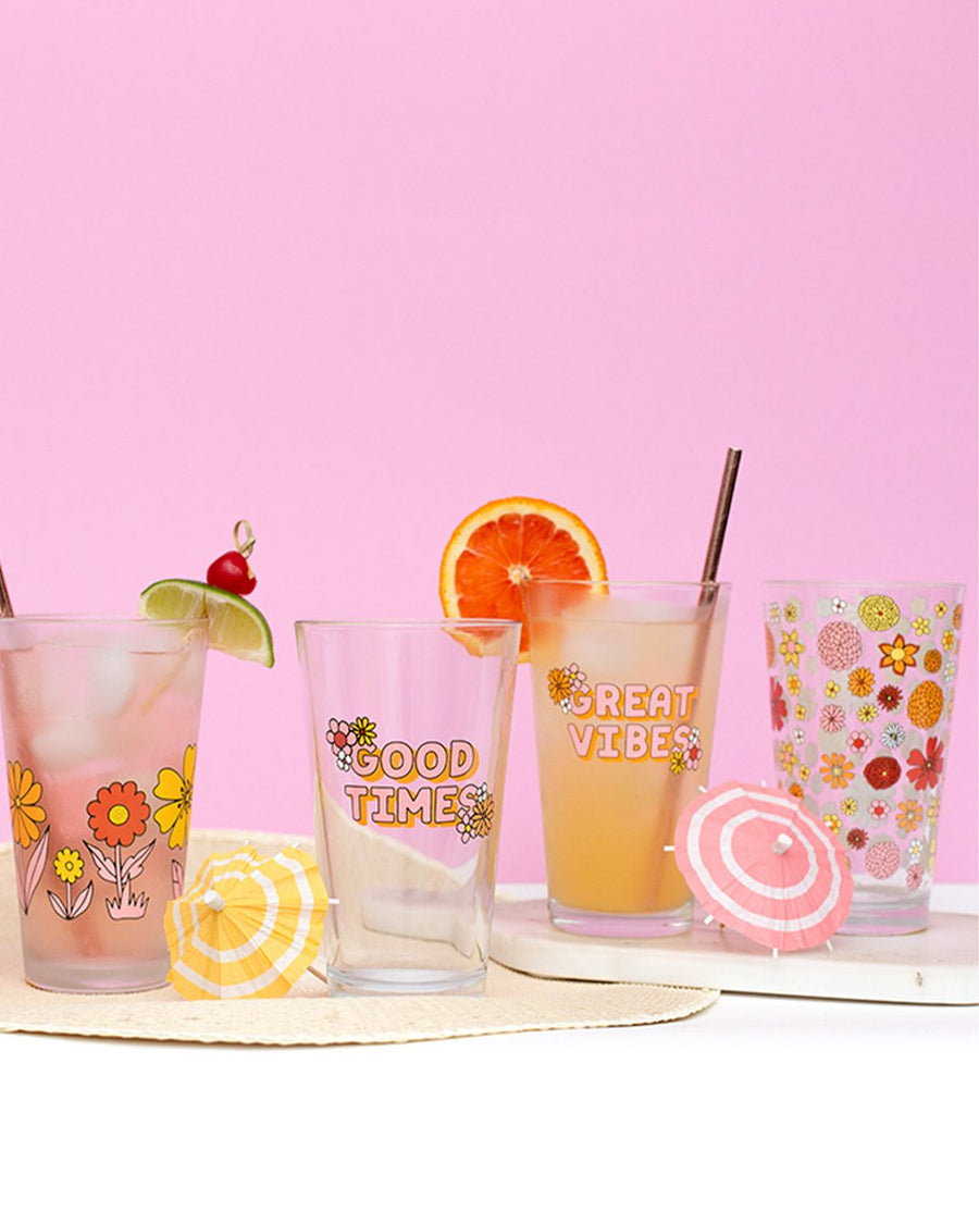 pint glasses filled with various beverages, fruit, and drink umbrellas