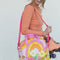 model holding pink, yellow, orange groovy print roller skate bag