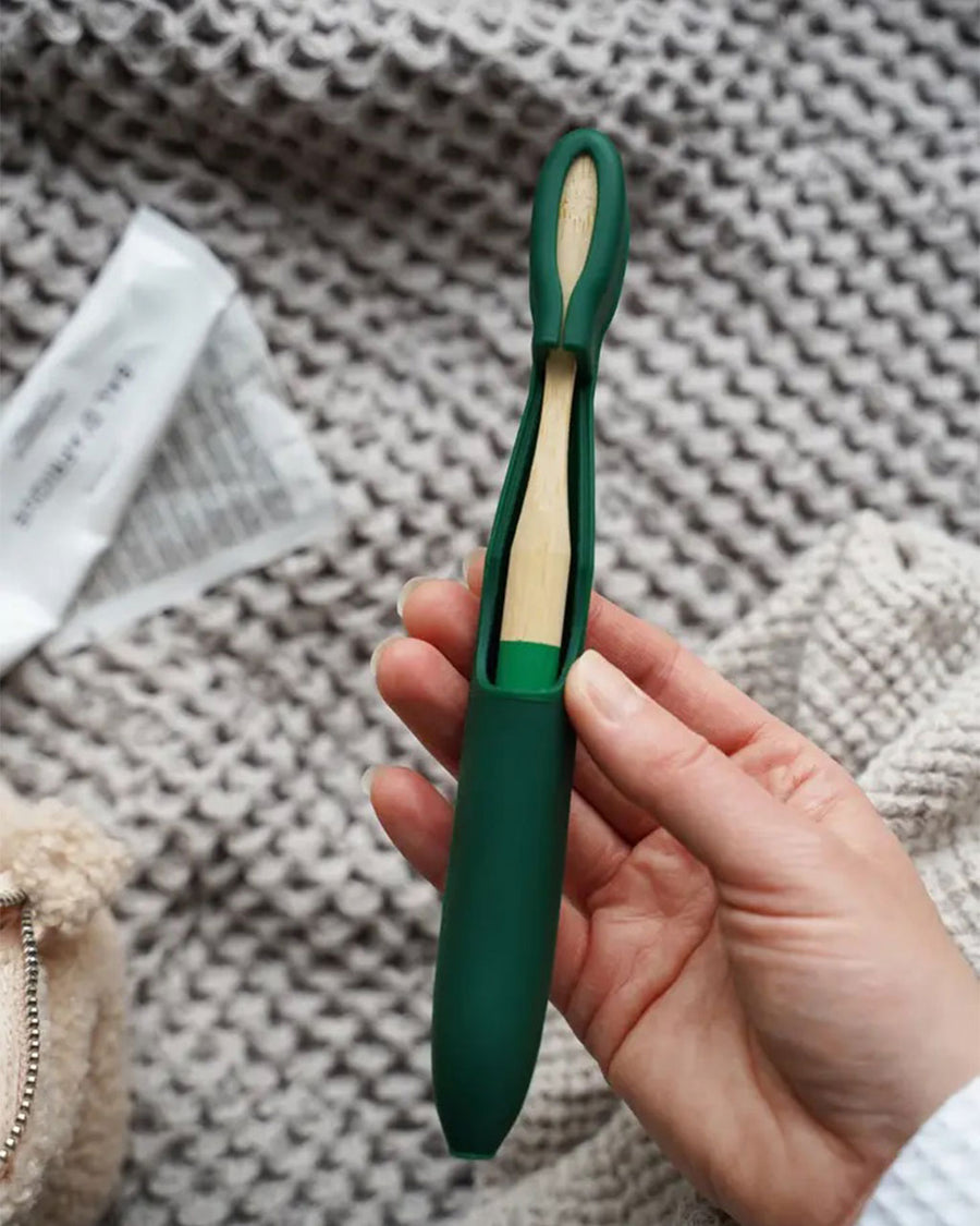model holding green bamboo toothbrush with matching cover