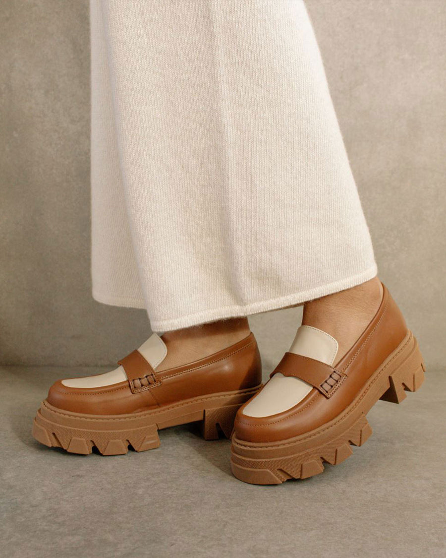model wearing tan platform loafers with cream accents and brown soles