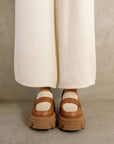 frontview of model wearing tan platform loafers with cream accents and brown soles