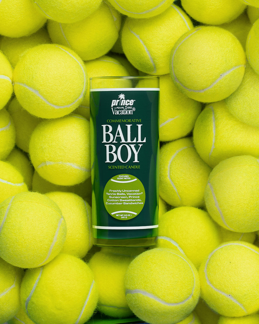 dark green ball boy candle on a pile of tennis balls