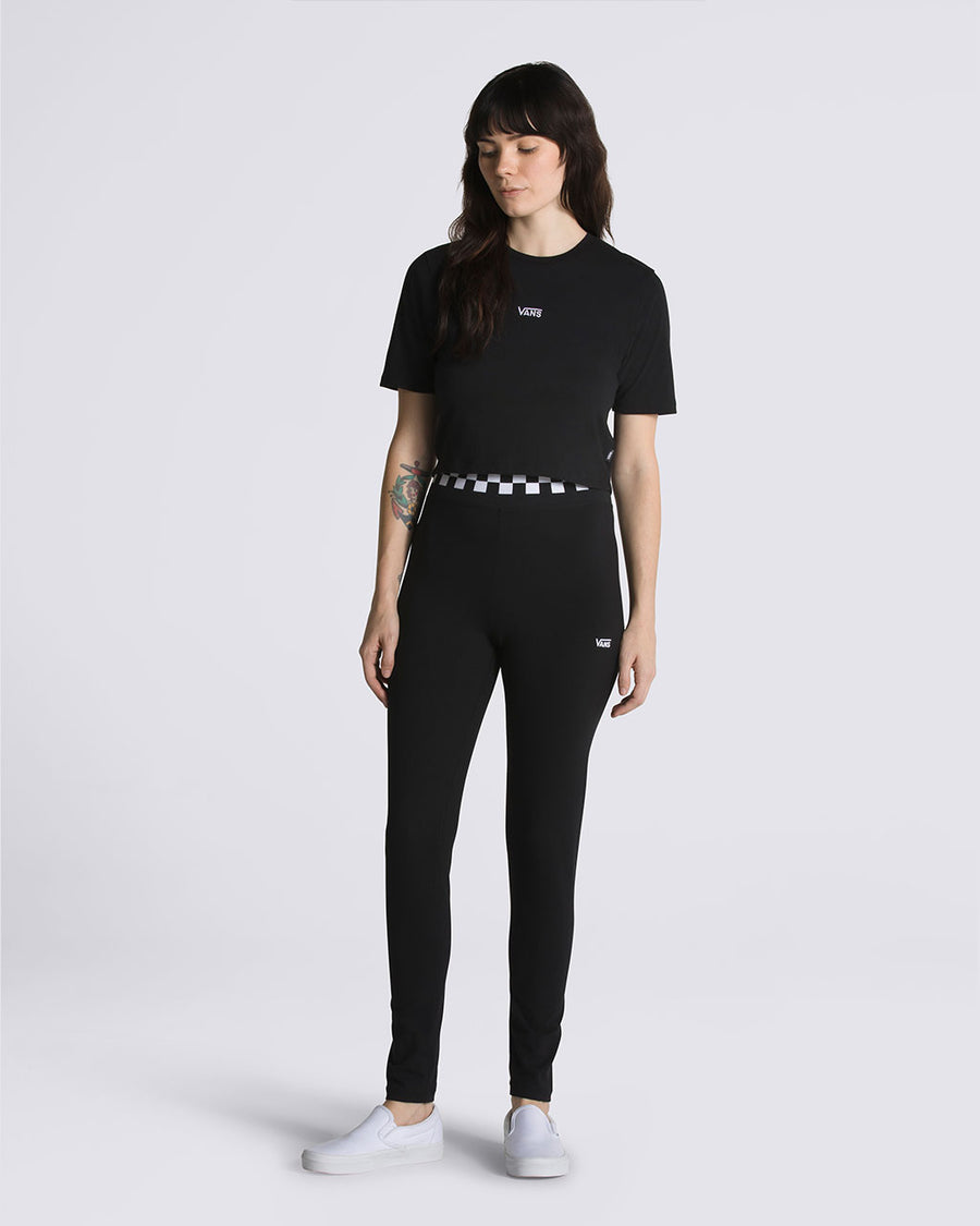 model wearing black leggings with white and black checkerboard waistband and vans logo on the leg