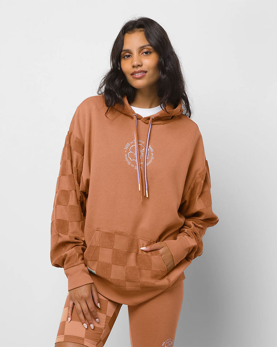 model wearing terracotta colored hoodie with fleece checker pocket, sleeves, and hood and embroidered vans front