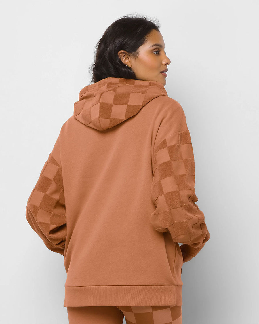back view of model wearing terracotta colored hoodie with fleece checker pocket, sleeves, and hood and embroidered vans front