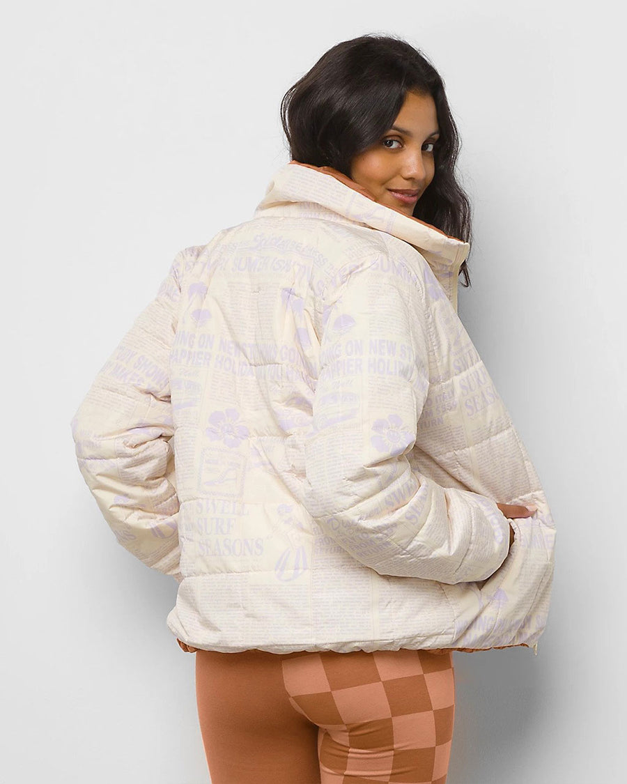 backview of model wearing reversible white + brown quilted jacket with lilac print  and biker shorts
