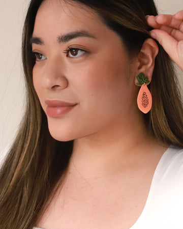 model wearing large papaya shaped earrings
