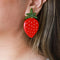 up close of model wearing large strawberry earrings