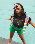 woman wearing black tshirt with "Stronger Than You Think" text graphic with green shorts and sunglasses
