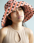 model wearing wide brim hat with multicolor plaid in the colors of brown, peach, pink and light pink