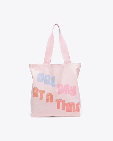 pink canvas tote with "ONE DAY AT A TIME" text graphic