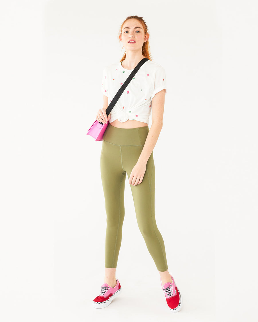 white cotton tee with a multi colored daisy pattern all over shown on model with olive colored leggings