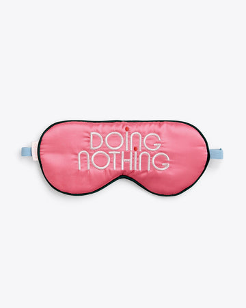 pink eye mask with "DOING NOTHING" text graphic and blue band