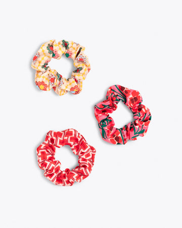 set of 3 scrunchies in various patterns: yellow patchwork, red and pink geometric pattern, bold red floral