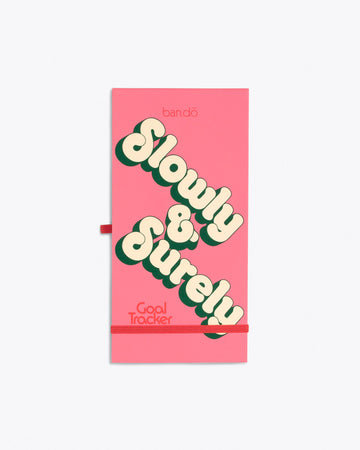 pink vertical notepad with "Slow & Surely" bubble text graphic with dark pink band and pen holder