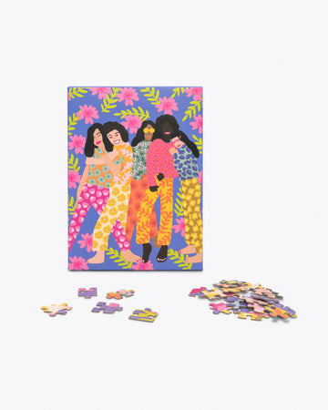 puzzle of illustration of 5 girls in bold floral print outfits against floral pattern shown as box with a few puzzle pieces in front
