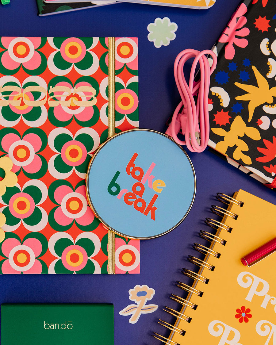 editorial image of charging pad with blue ground and multicolor 'take a break' text on the front. also comes with pink charging cable