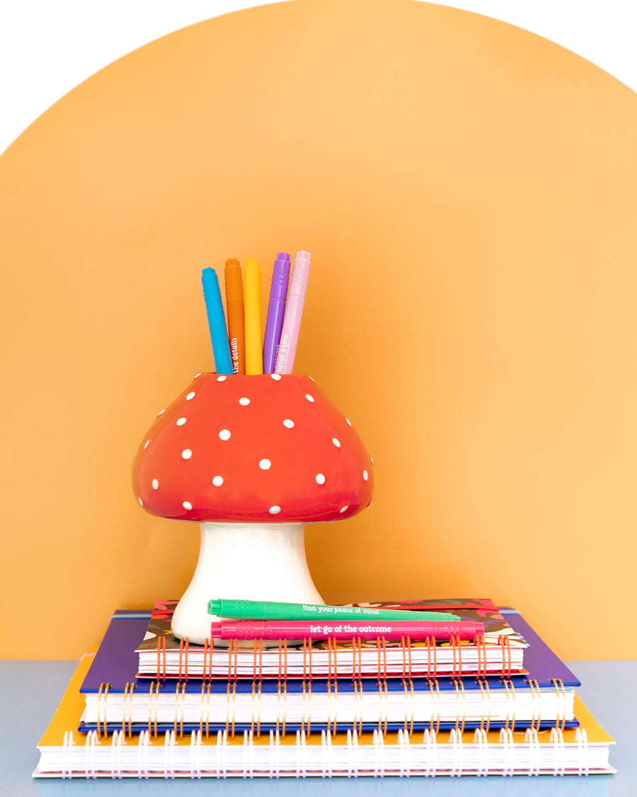 editoral image of editorial image of mushroom vase with red top and white polka dots and white stem holding pens