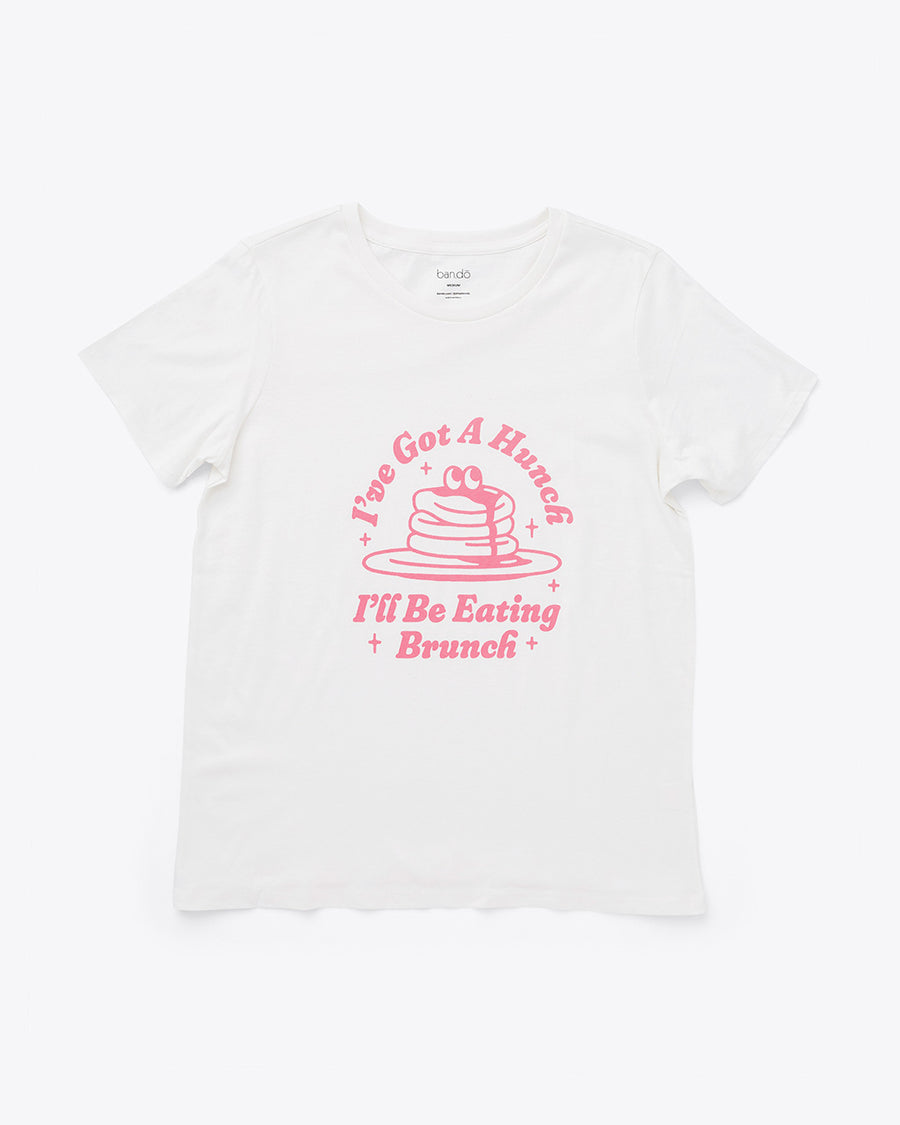 white crewneck tee with 'i've got a hunch i'll be eating brunch' and pancake graphic in pink lettering