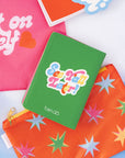 back view of green passport holder with colorful 'howdy' across the front