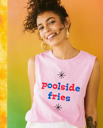 model wearing pink muscle tank with the words poolside fries in red and blue lettering paired with white bottoms