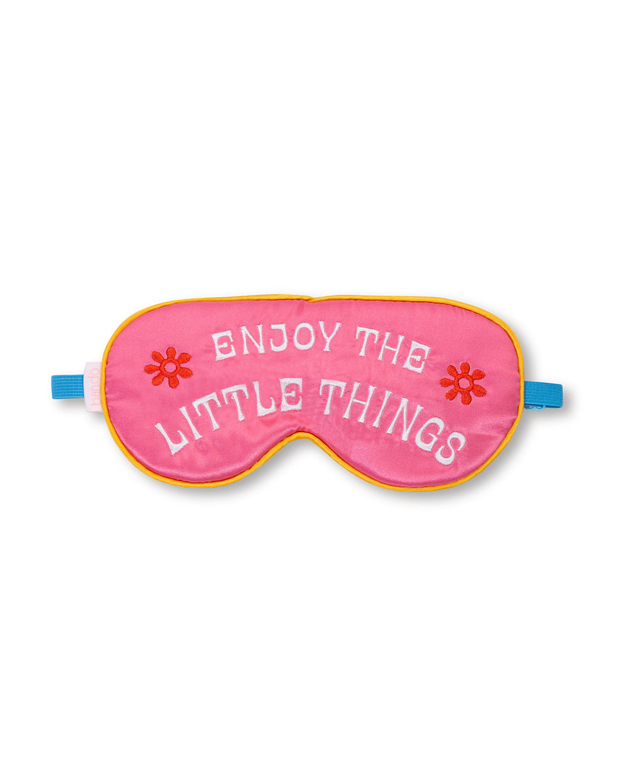 pink eye mask with "ENJOY THE LITTLE THINGS" text graphic and blue band