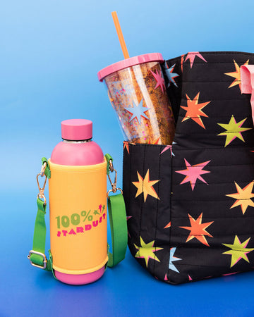editorial image of pink stainless steel water bottle with yellow and green water bottle sling with the words '100% stardust' across the front