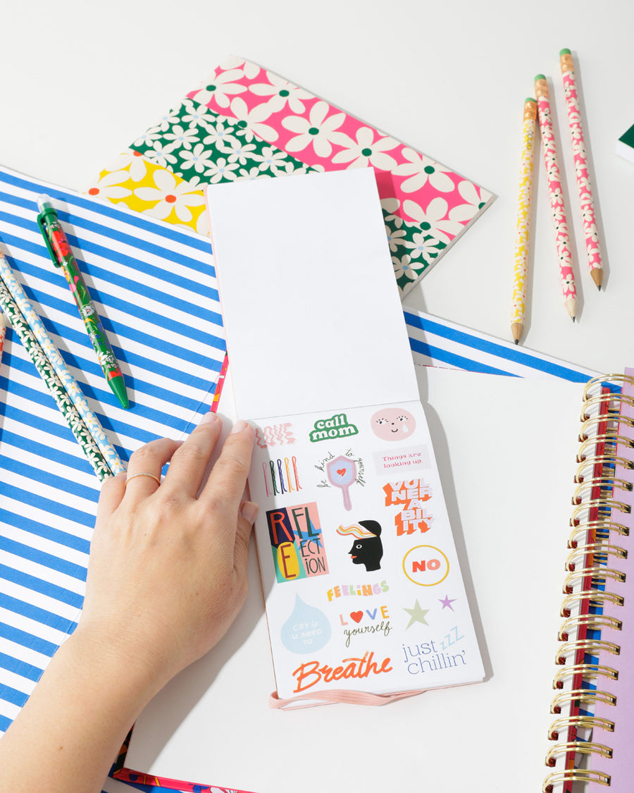 lifestyle image of sticker book shown with a bando planner and other bando products