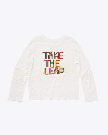 white boxy long sleeve tee with "TAKE THE LEAP" text graphic in multicolor font