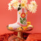 editorial image of pink cowboy boot vase with yellow and floral accents