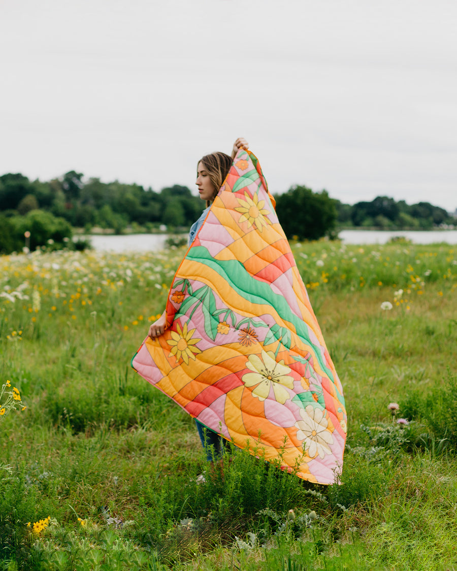 model holding multi color groovy print puffy blanket in orange, pink, yellow and green colors