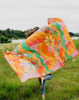 model running with multi color groovy print puffy blanket in orange, pink, yellow and green colors in a field