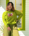 Woman wearing green long sleeved sweater with butterfly on the front