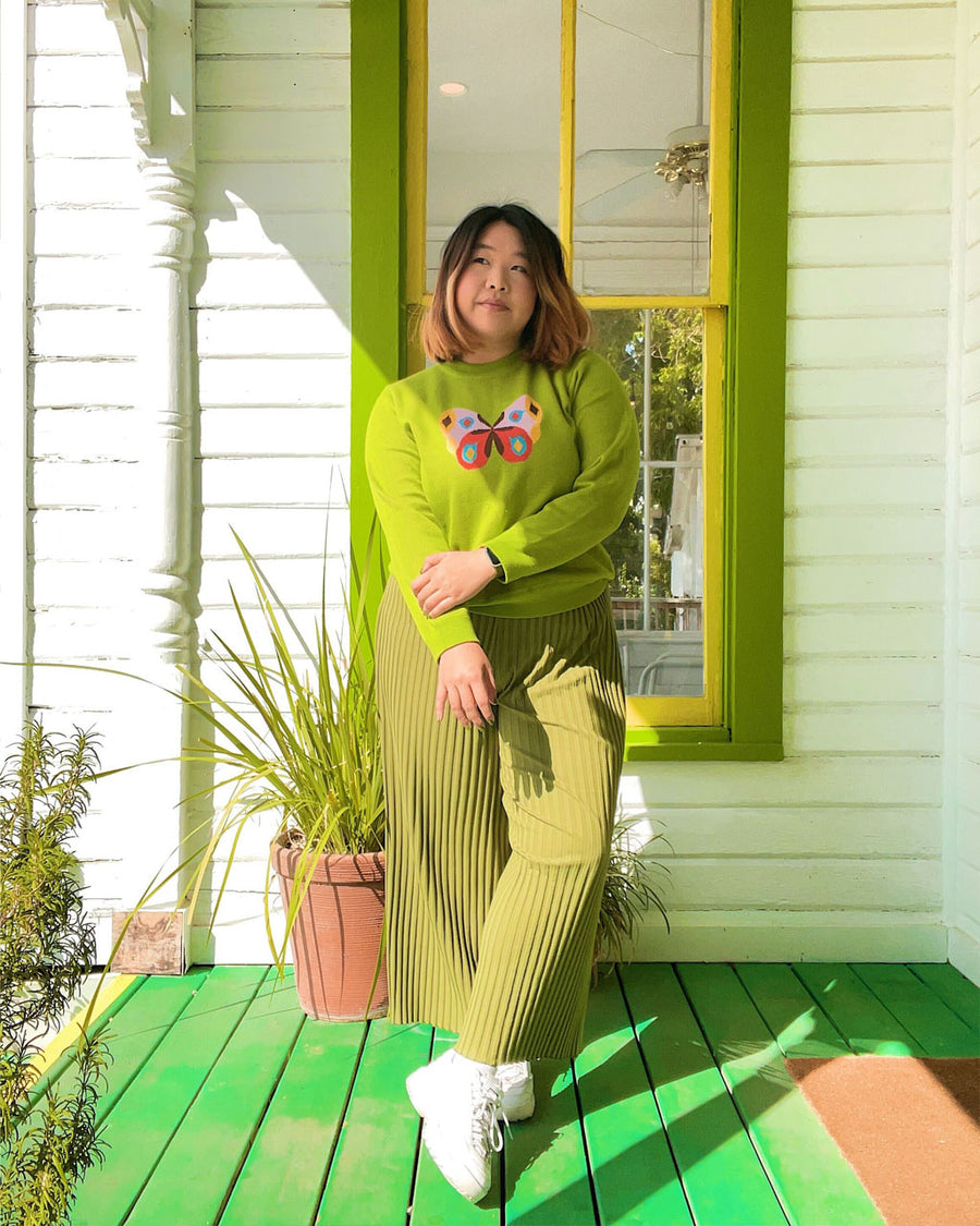 Woman in a green outfit standing on a green front porch